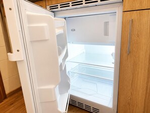 A white refrigerator with a freezer compartment on top and a main compartment below.