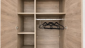 A wooden wardrobe with multiple compartments and a hanging rod.