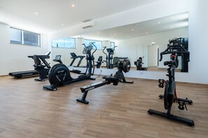 Ein Fitnessstudio mit verschiedenen Trainingsgeräten, darunter Laufbänder, Ergometer und Kraftgeräte.