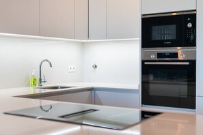 Eine moderne Küche mit Einbau-Mikrowelle, Backofen und Spüle aus Edelstahl.
