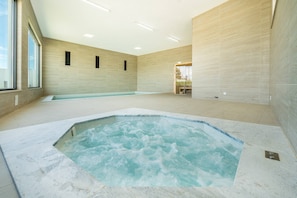 Ein Wellnessbereich mit Whirlpool und Schwimmbad, Fliesenwänden und großen Fenstern.