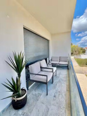 A balcony with a seating area, a potted plant, and a view of the sky. - Cabanas de Tavira - Sunrise Vibes (Tavira)