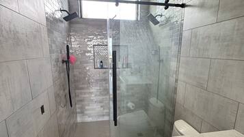 A modern bathroom with a glass shower enclosure, a toilet, and a vanity with a sink.