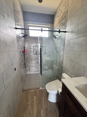 A modern bathroom with a glass shower enclosure, a toilet, and a vanity with a sink.