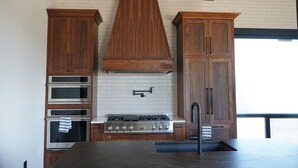 A modern kitchen with wooden cabinets, stainless steel appliances, and a large island. - Chelan Ridge (Chelan)