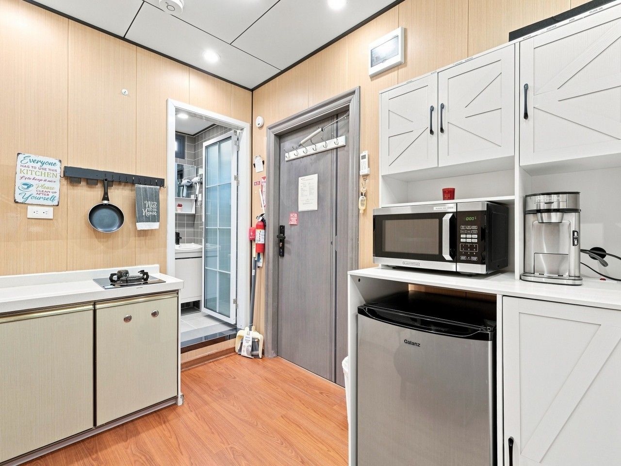 A modern kitchen with white cabinetry, a built-in microwave, a coffee maker, and a dishwasher.