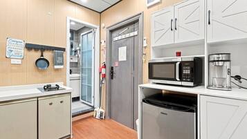 A modern kitchen with white cabinetry, a built-in microwave, a coffee maker, and a dishwasher.
