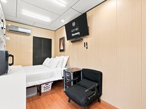 A hotel room with a bed, a desk, a chair, a television, and a wall-mounted sign. - The Sun Residence #3 at Kosmos Sanctuary (Phoenix)