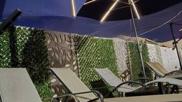 Outdoor lounge chairs and umbrellas, suggesting a seating area.