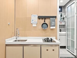 Een moderne keuken met een spoelbak van roestvrij staal, een gasfornuis en een hangende pan.