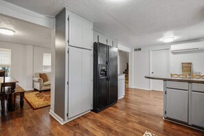 Eine moderne Küche mit einem schwarzen Kühlschrank, Holzboden und weißen Schränken.
