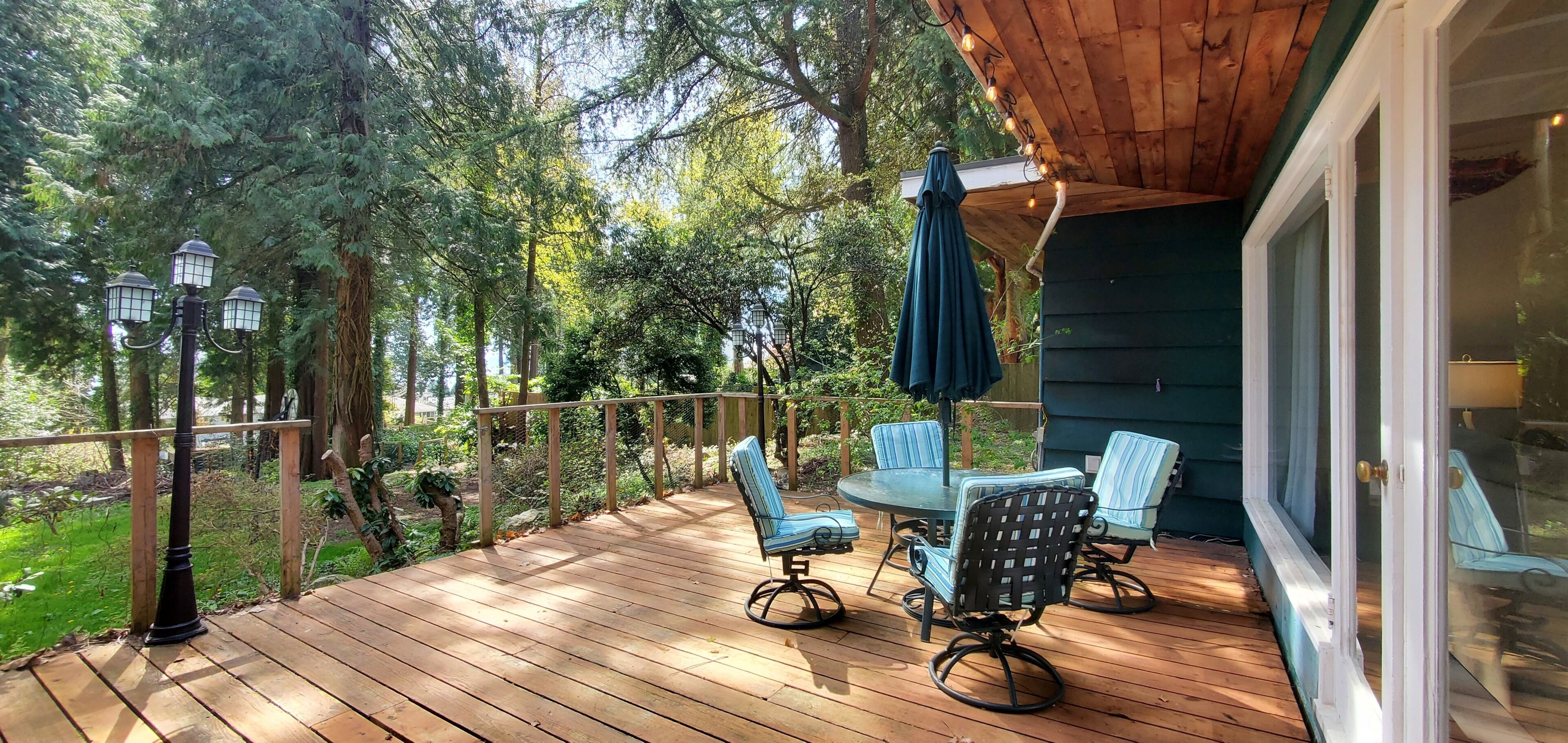 A wooden deck with outdoor furniture and a view of the surrounding forest.