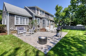A house with a patio, outdoor furniture, and a grill. - Welcome to Lewis Bay Celtic Cottage tucked on a quiet street close to the beach (Yarmouth)