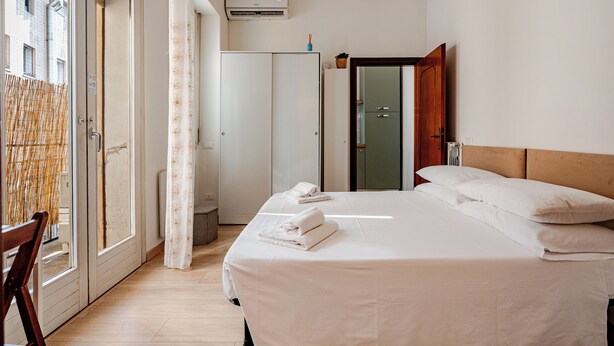 A hotel room with a bed, a wardrobe, a bathroom, and a view of the outside. - Casa Toli Padua - Self-Check-In, Wi-Fi, 2 Minutes from the Train Station (Padova)