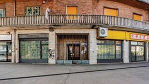 A building with a brick facade, multiple closed shop fronts, and a gated entrance. - Casa Toli Padua - Self-Check-In, Wi-Fi, 2 Minutes from the Train Station (Padova)