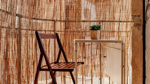 A room with a bamboo wall, a wooden chair, and a small table with a plant. - Casa Toli Padua - Self-Check-In, Wi-Fi, 2 Minutes from the Train Station (Padova)