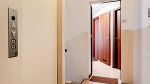 A hotel corridor with a fire safety sign, an elevator, and a door leading to a room. - Casa Toli Padua - Self-Check-In, Wi-Fi, 2 Minutes from the Train Station (Padova)