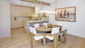 Eine moderne Küche mit Holzschränken, einer zentralen Kochinsel und einem Essbereich mit rundem Tisch und Stühlen.