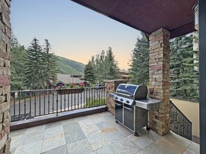 An outdoor patio with a barbecue grill, stone pillars, and a view of a mountain landscape. - Modern Vail Townhome for Families & Friends - 3 Bed + Loft - Close to Bus (Vail)