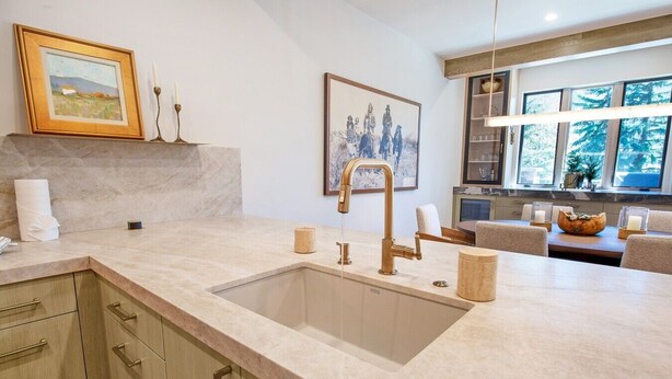 Eine Küche mit einem großen Spülbecken, Holzschränken und einem Essbereich mit Tisch und Stühlen.