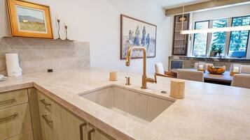 Una cocina con un lavaplatos grande, armarios de madera y un comedor con una mesa y sillas.
