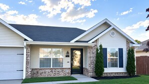 A single-story house with a front porch, a garage, and a brick foundation.