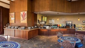 A restaurant with a wooden counter, buffet, and seating area with patterned tables and wicker chairs. - Family-Friendly 2BR in Paradise – Kings’ Land, Hawaii (Waimea)