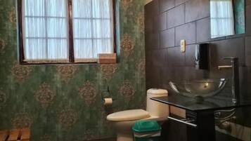 Et badeværelse med toilet, håndvask og vindue.