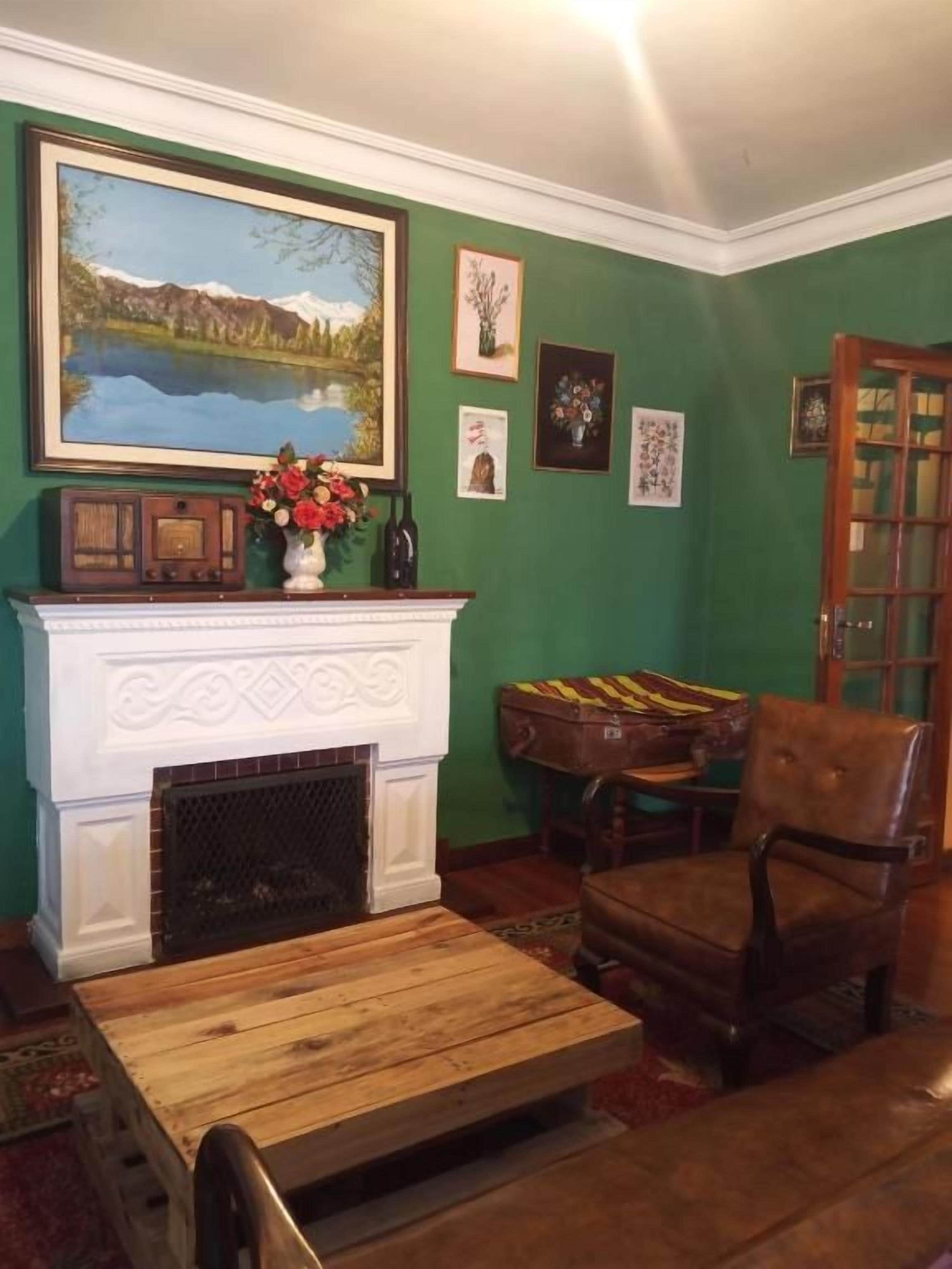A room with a fireplace, a chair, a table, and a painting on the wall.