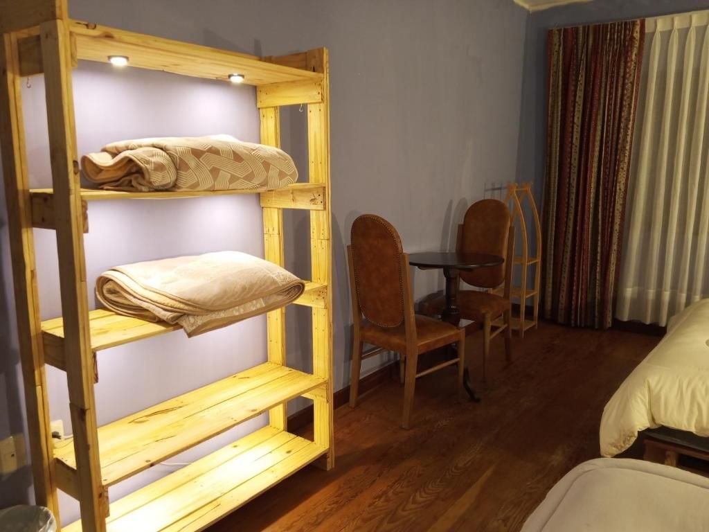 Une chambre avec un lit superposé, un bureau avec deux chaises et une fenêtre avec des rideaux.