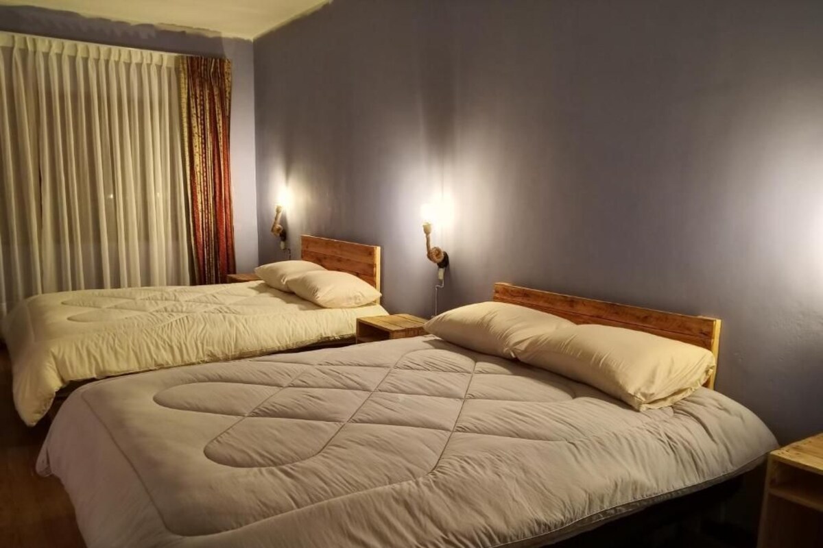 A hotel room with two beds, wooden headboards, and bedside lamps.