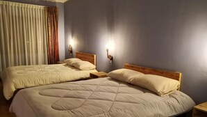 A hotel room with two beds, wooden headboards, and bedside lamps.