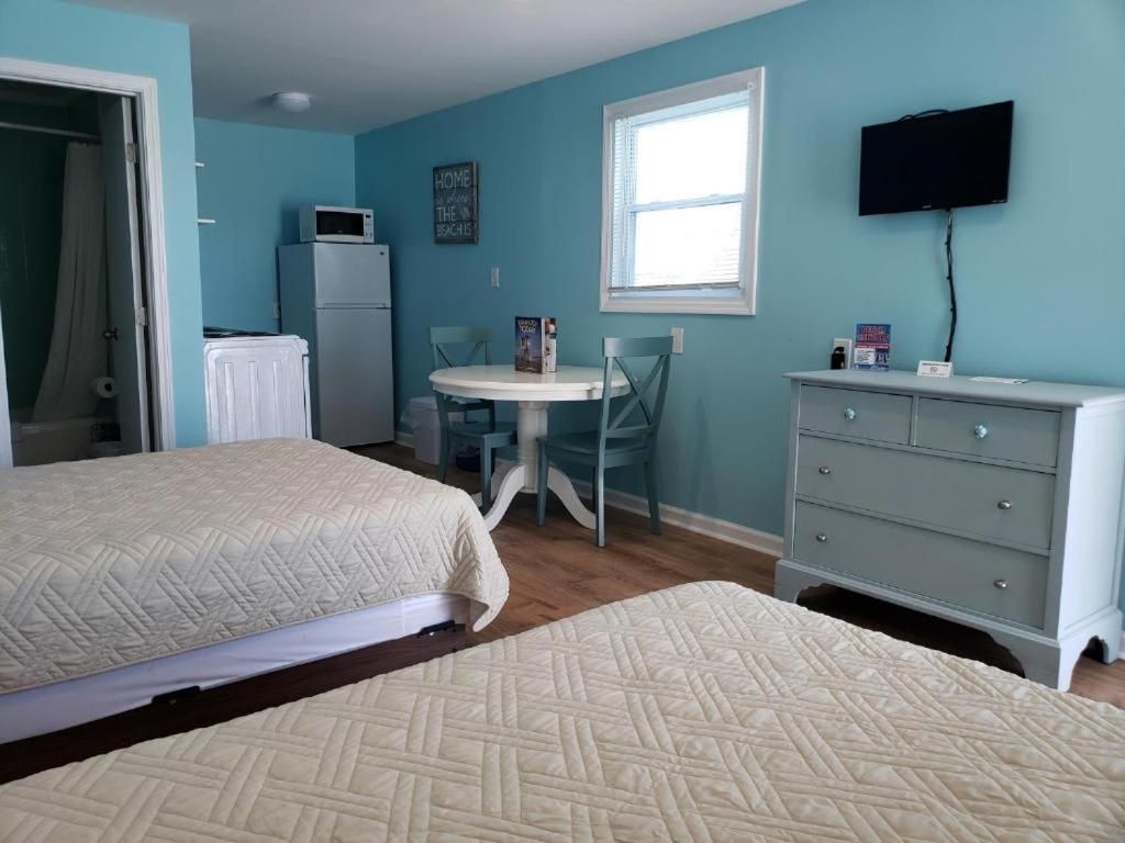 A room with two beds, a small table, a television, and a window.