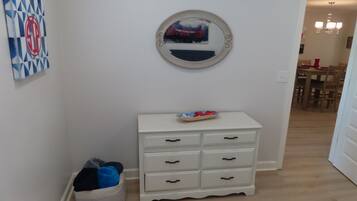 A hallway with a white dresser, a round mirror, and a wall art piece.