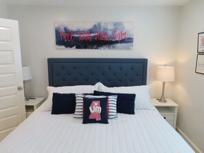 A bedroom with a large bed, a dark headboard, and a wall-mounted sign. - Walk to the Grove! Perfect Game Day Condo! (Oxford)