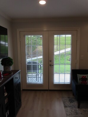A room with a double door, a small table with a plant, and a bench with a cushion.