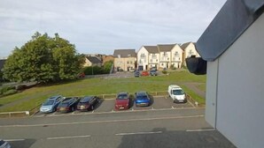 A parking lot with multiple cars and a building in the background. - The Rookery  (Grays)