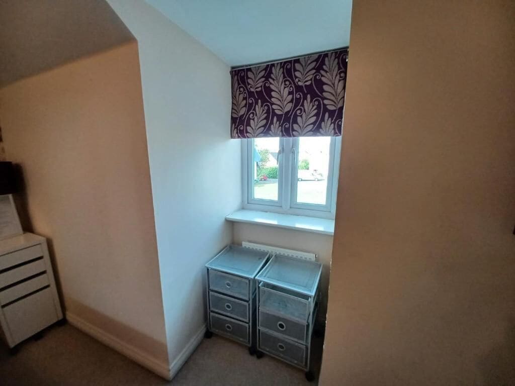 A corner room with a window, a radiator, and two storage units.