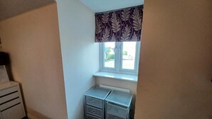 A corner room with a window, a radiator, and two storage units. - The Rookery  (Grays)