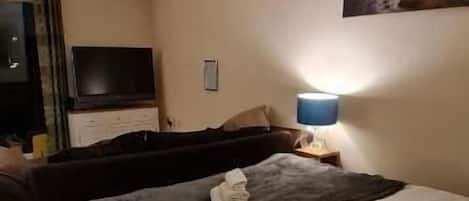 A bedroom with a bed, a TV, a lamp, and a painting on the wall.