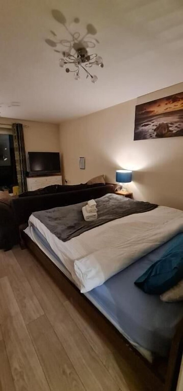 Une chambre à coucher avec un lit, une télévision, une lampe et un tableau au mur.