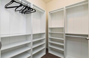 A walk-in closet with multiple shelves and hanging space. - Des Moines Ranch near Altoona | Fenced Yard, 3BR (Des Moines)