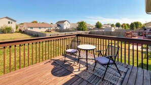 A wooden deck with a table and chairs, surrounded by a wooden fence, overlooking a residential area. - Des Moines Ranch Retreat (Des Moines)