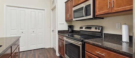 Una cocina con gabinetes de madera, microondas, estufa y encimera.