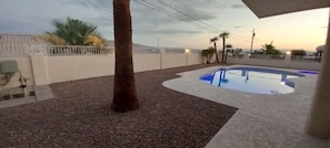 Ein Schwimmbecken mit geschwungener Kante, umgeben von einer Betonplattform und einer weißen Wand.