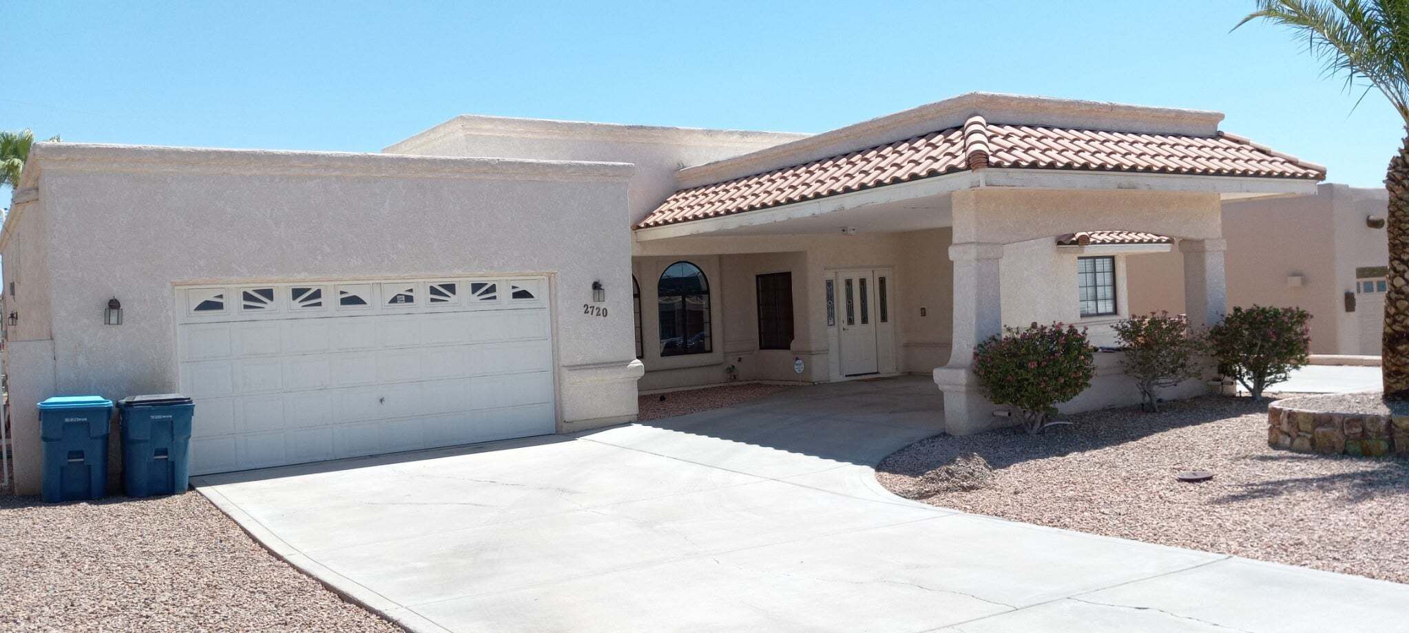 Ein Wohnhaus mit Garage, überdachter Veranda und kleinem Garten.