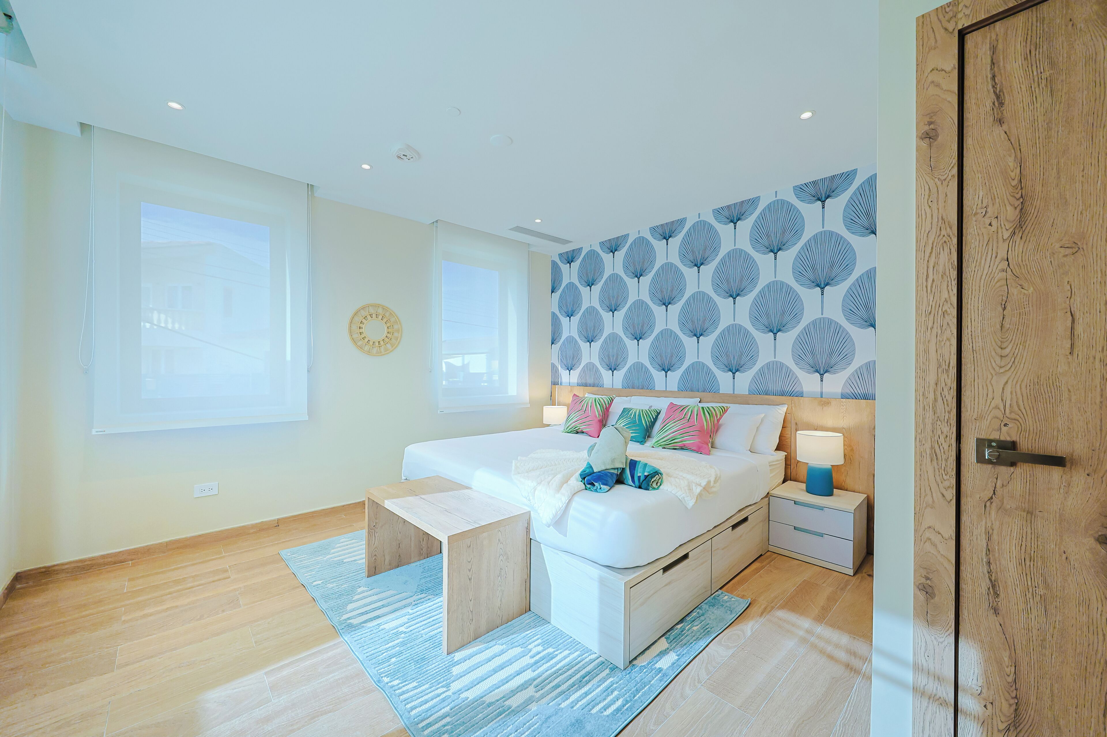 A modern bedroom with a large bed, bedside tables, a wooden door, and a patterned wall.