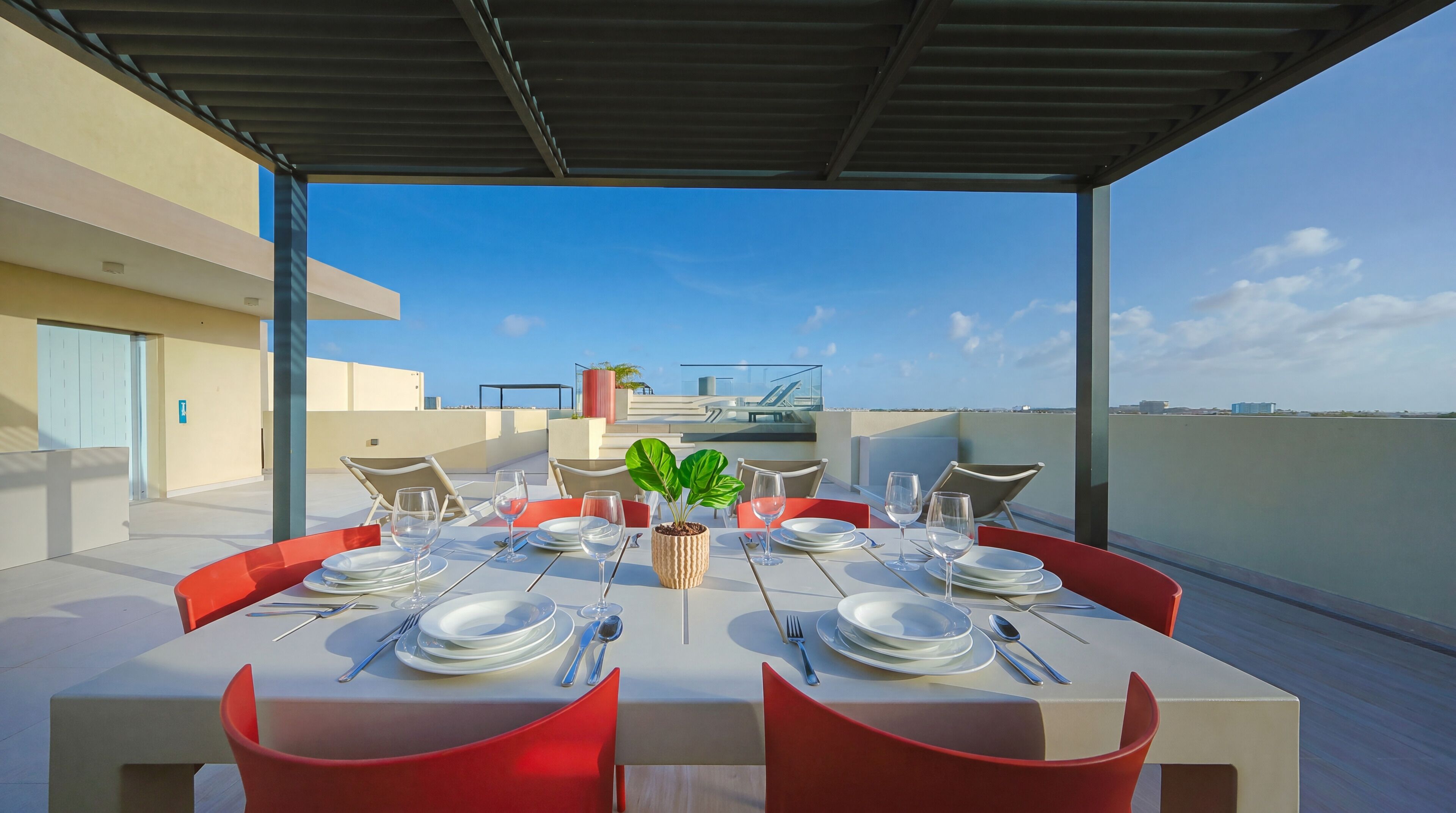 Área de refeições no terraço, com uma mesa posta para quatro pessoas, com vista para a paisagem urbana.