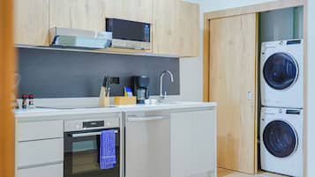 Uma cozinha compacta com micro-ondas, cafeteira e máquina de lavar integrada.