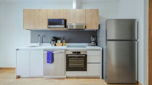A modern kitchen with white cabinetry, a stainless steel refrigerator, a microwave, a Bosch oven, and a dishwasher. - Bonsai Boutique by BlueAruba Rentals (Noord)